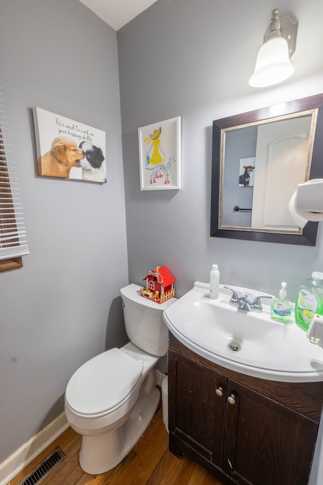 bathroom featuring toilet, vanity, and hardwood / wood-style flooring