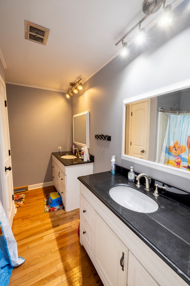 bathroom featuring crown molding, rail lighting, wood-type flooring, and large vanity