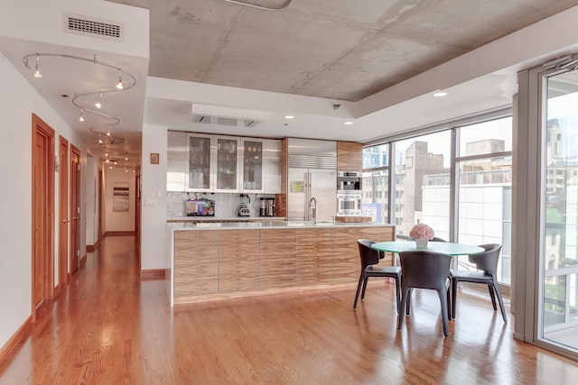 kitchen featuring stainless steel appliances, light countertops, visible vents, light wood-style flooring, and modern cabinets