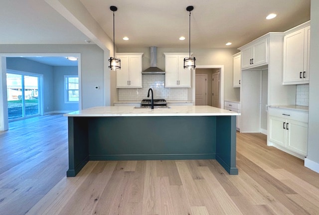 kitchen featuring wall chimney range hood, light hardwood / wood-style floors, and decorative light fixtures