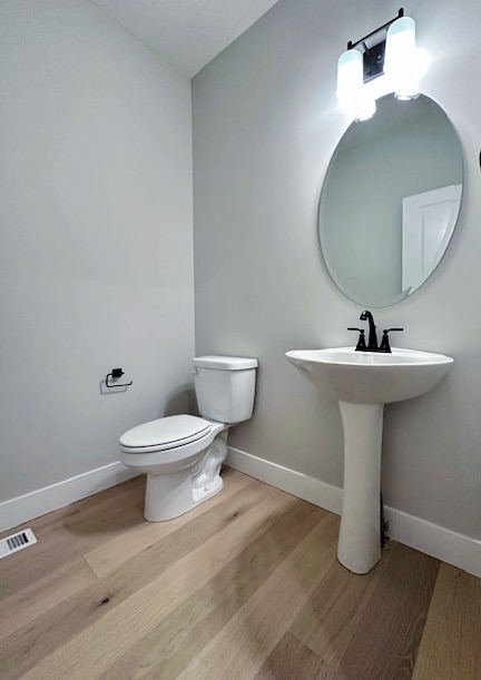 bathroom with toilet and wood-type flooring