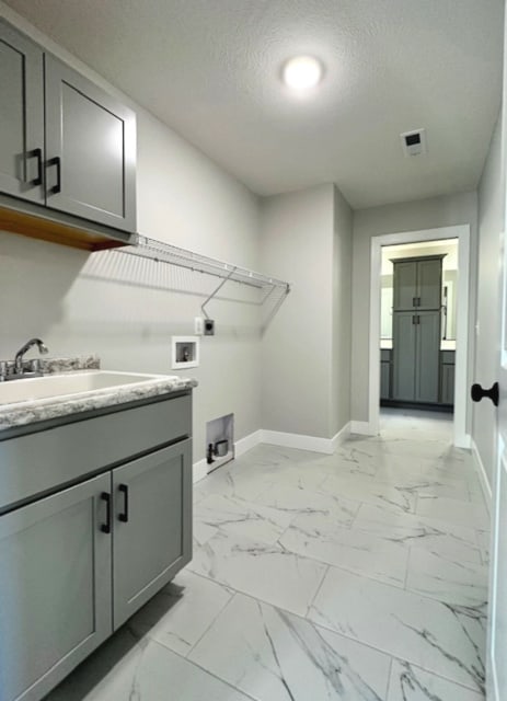 laundry room with cabinets, light tile floors, hookup for a washing machine, electric dryer hookup, and a textured ceiling