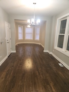 unfurnished room with a notable chandelier and dark hardwood / wood-style floors