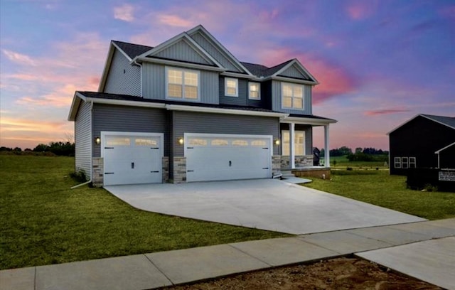 craftsman inspired home featuring a yard, stone siding, an attached garage, and driveway