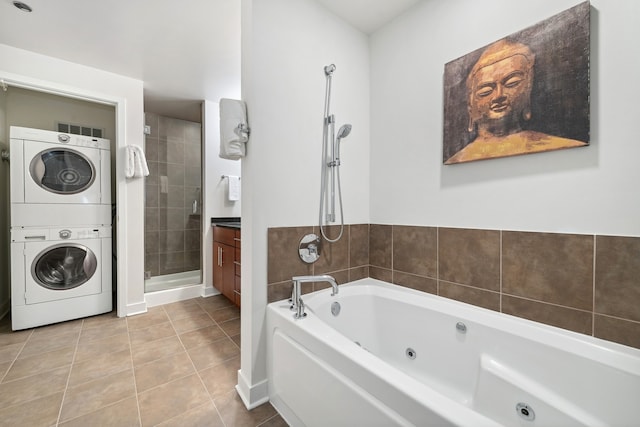 bathroom featuring tile flooring, a bathtub, vanity, and stacked washing maching and dryer