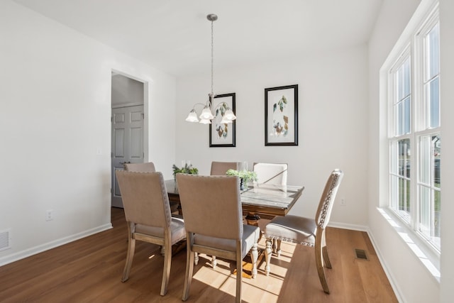 dining space with hardwood / wood-style floors and an inviting chandelier