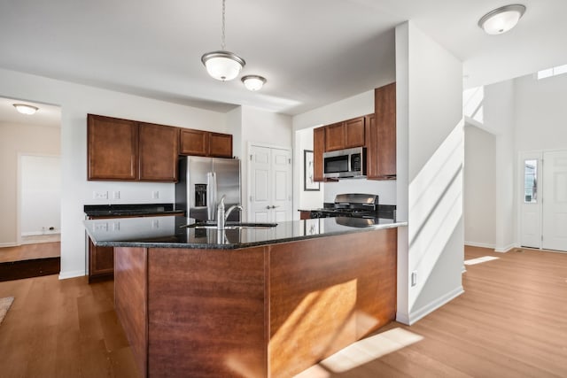 kitchen with stainless steel appliances, hanging light fixtures, hardwood / wood-style flooring, and sink