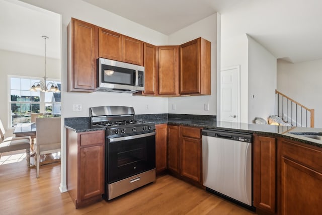 kitchen featuring stainless steel appliances, pendant lighting, light wood-type flooring, and a notable chandelier