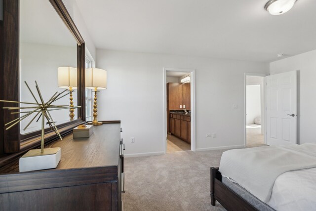 bedroom featuring ensuite bath and light colored carpet