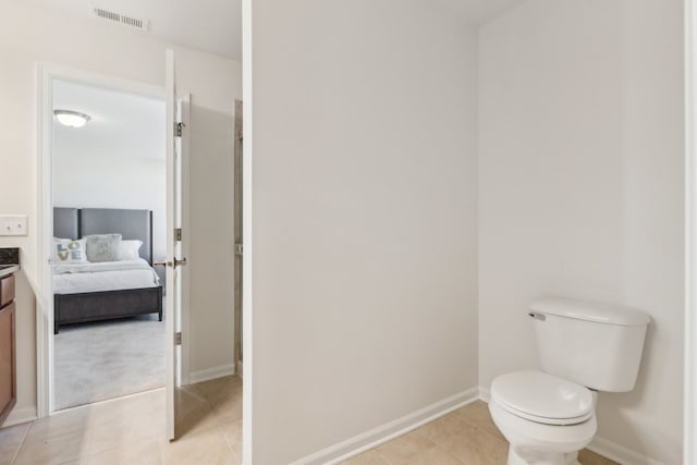 bathroom with toilet, vanity, and tile patterned flooring