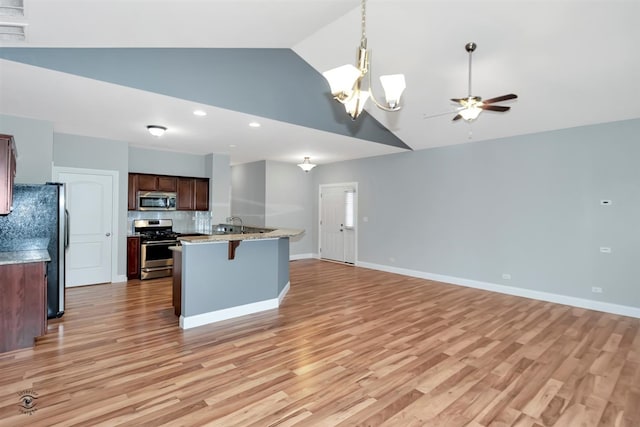 kitchen with appliances with stainless steel finishes, backsplash, light hardwood / wood-style floors, and decorative light fixtures