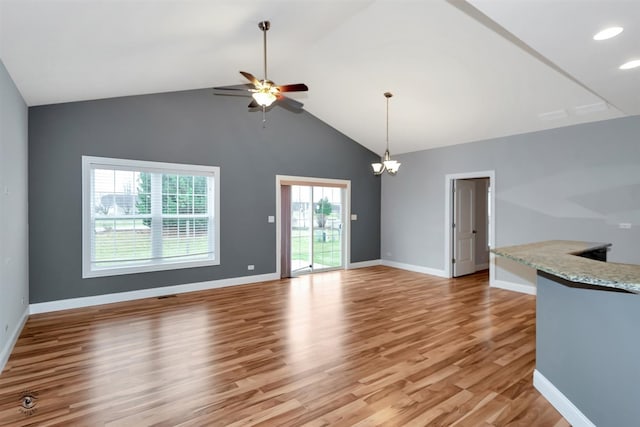 unfurnished room featuring high vaulted ceiling, light hardwood / wood-style flooring, and ceiling fan with notable chandelier