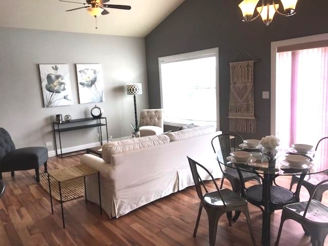 living room featuring lofted ceiling, ceiling fan with notable chandelier, and dark hardwood / wood-style floors