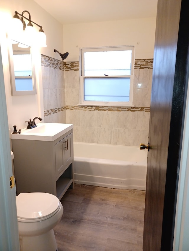 full bathroom with tiled shower / bath combo, hardwood / wood-style floors, toilet, and vanity