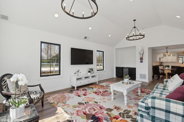 living room featuring hardwood / wood-style flooring, a chandelier, and vaulted ceiling