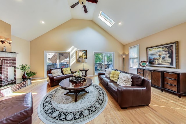 living room featuring light wood-type flooring, a skylight, ceiling fan, and a healthy amount of sunlight