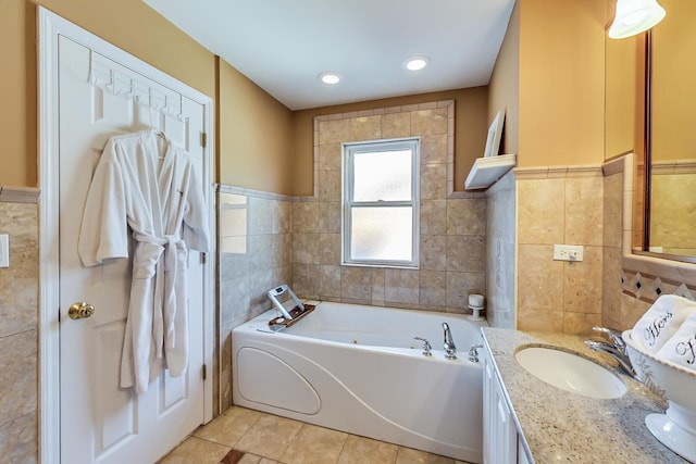 bathroom with tile walls, tile patterned flooring, a bathtub, and vanity