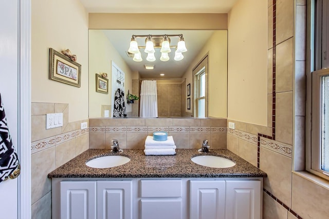 bathroom with a chandelier, vanity, and tile walls