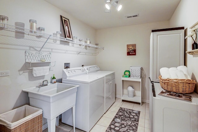 washroom with sink, independent washer and dryer, and light tile patterned floors