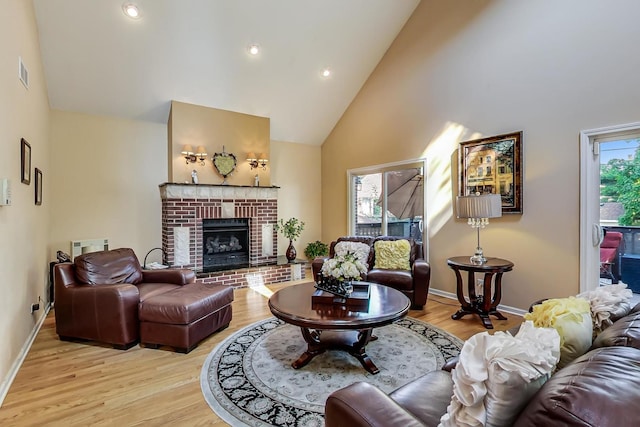 living room featuring high vaulted ceiling, a fireplace, light hardwood / wood-style floors, and plenty of natural light