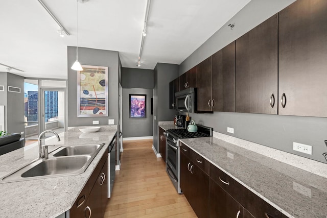 kitchen featuring appliances with stainless steel finishes, rail lighting, sink, pendant lighting, and light hardwood / wood-style flooring