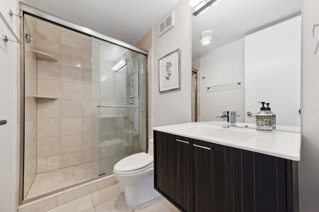 bathroom featuring tile patterned floors, vanity, toilet, and a shower with door