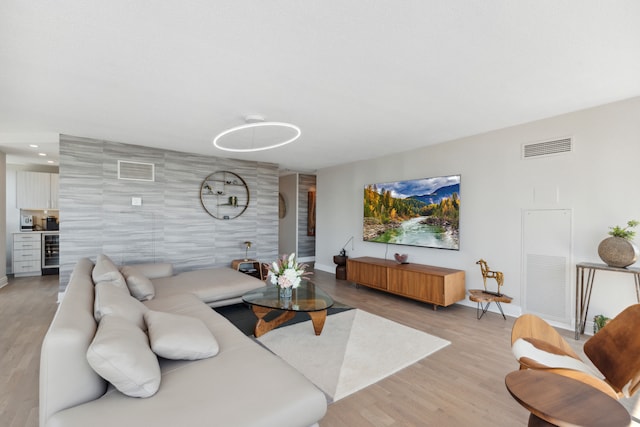 living room featuring wine cooler, light hardwood / wood-style flooring, and tile walls