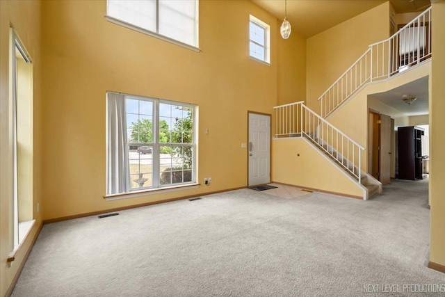 422 Rachel Cir, Romeoville, IL 60446 - unfurnished living room featuring carpet flooring, a high ceiling, and stairs