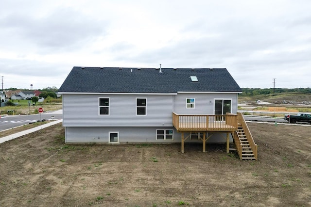 rear view of house with a deck, roof with shingles, and stairway