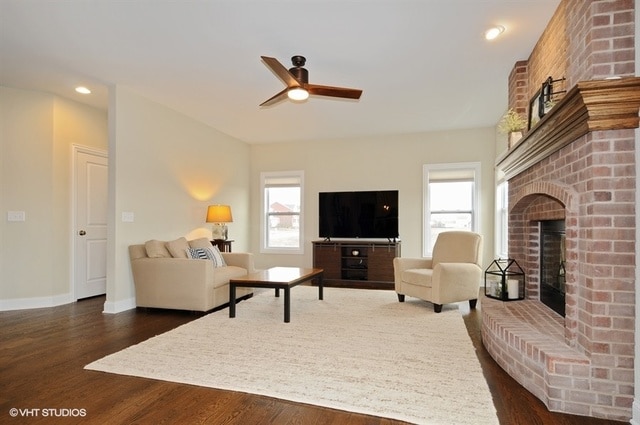 living room with a wealth of natural light, brick wall, dark hardwood / wood-style floors, and a fireplace