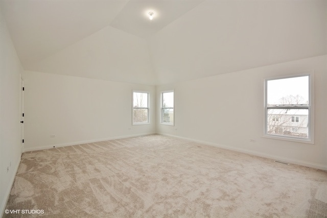 carpeted empty room with lofted ceiling and plenty of natural light