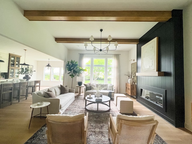 living room featuring light hardwood / wood-style flooring, beam ceiling, a chandelier, and a large fireplace