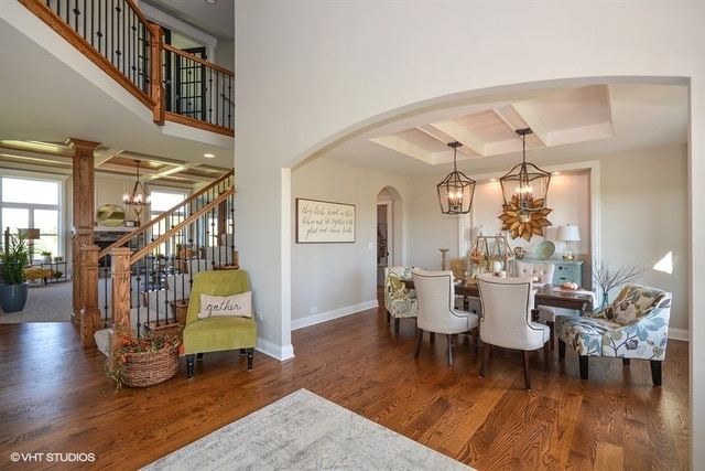 interior space featuring an inviting chandelier, dark wood-type flooring, and decorative columns