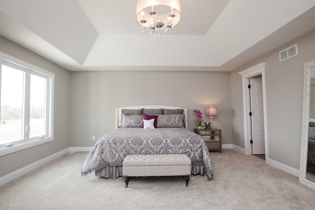 carpeted bedroom with a chandelier and a raised ceiling