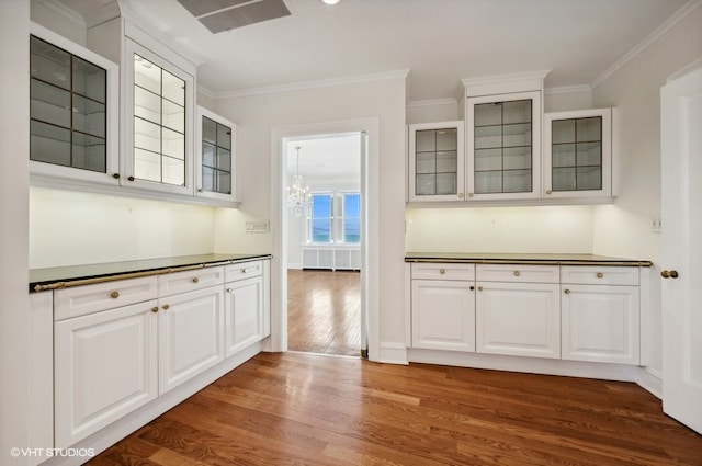 kitchen featuring white cabinets, wood-type flooring, crown molding, and an inviting chandelier