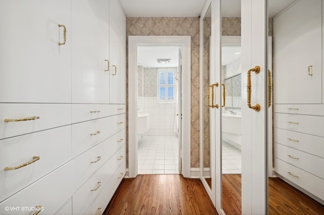 interior space with wood-type flooring, a bath, and tile walls