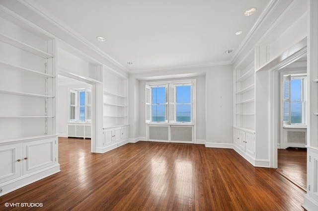 empty room with built in shelves, crown molding, dark wood-type flooring, and radiator heating unit