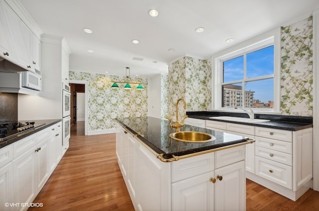 kitchen featuring white appliances, light hardwood / wood-style floors, white cabinets, sink, and a center island