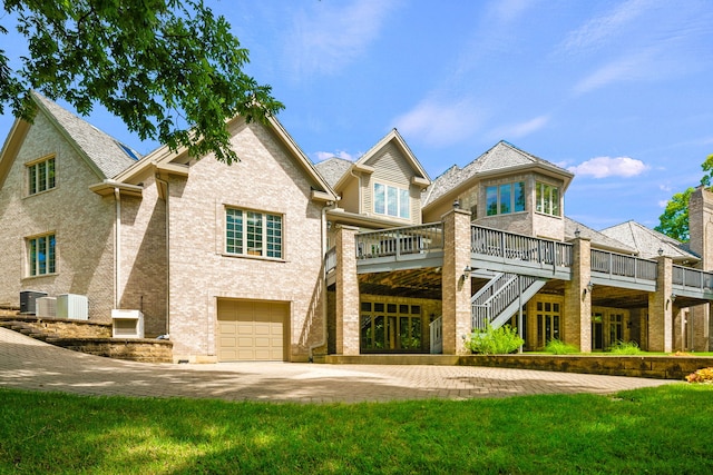 rear view of property featuring a garage, a yard, and a deck