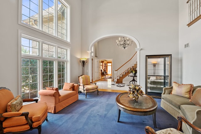 living room with a high ceiling, hardwood / wood-style floors, ornate columns, and an inviting chandelier