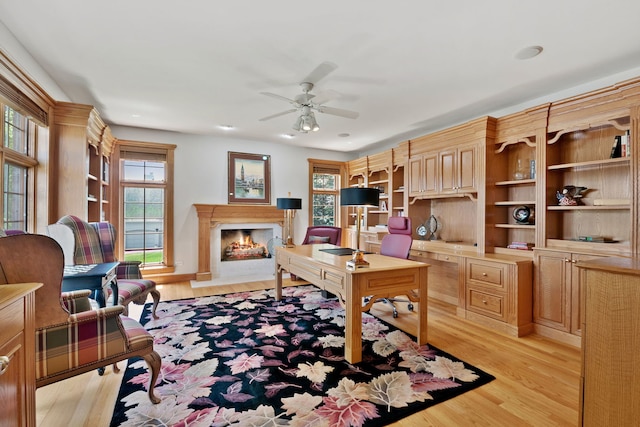 office space with a fireplace, light wood-type flooring, and ceiling fan