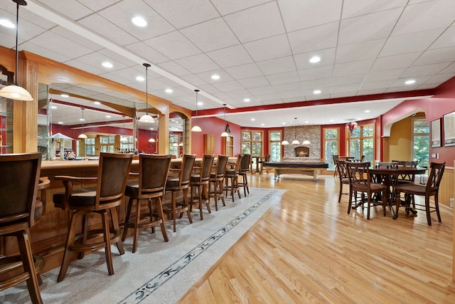 dining room featuring light hardwood / wood-style floors, a drop ceiling, and bar