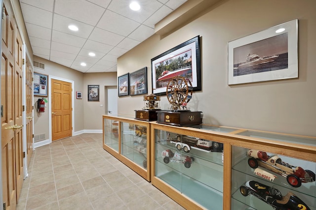 hallway featuring light tile patterned flooring and a paneled ceiling