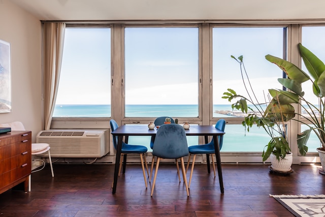 dining area with an AC wall unit, dark hardwood / wood-style floors, and a water view