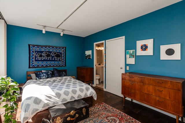 bedroom featuring dark wood-type flooring, rail lighting, and ensuite bathroom