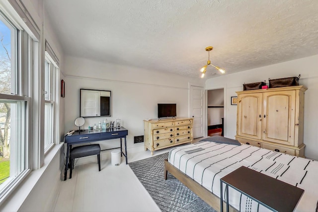 bedroom with a textured ceiling and multiple windows