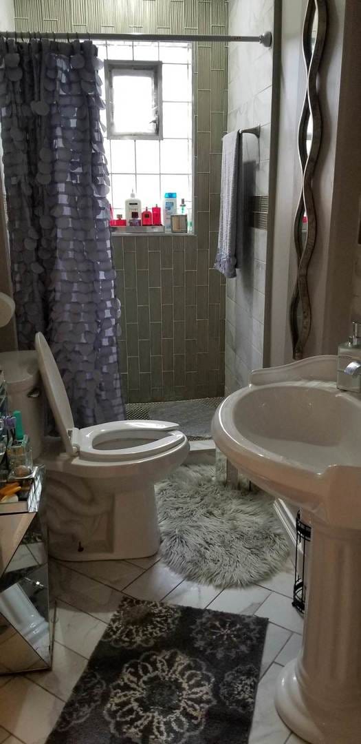 bathroom featuring walk in shower, tile flooring, toilet, and ornate columns