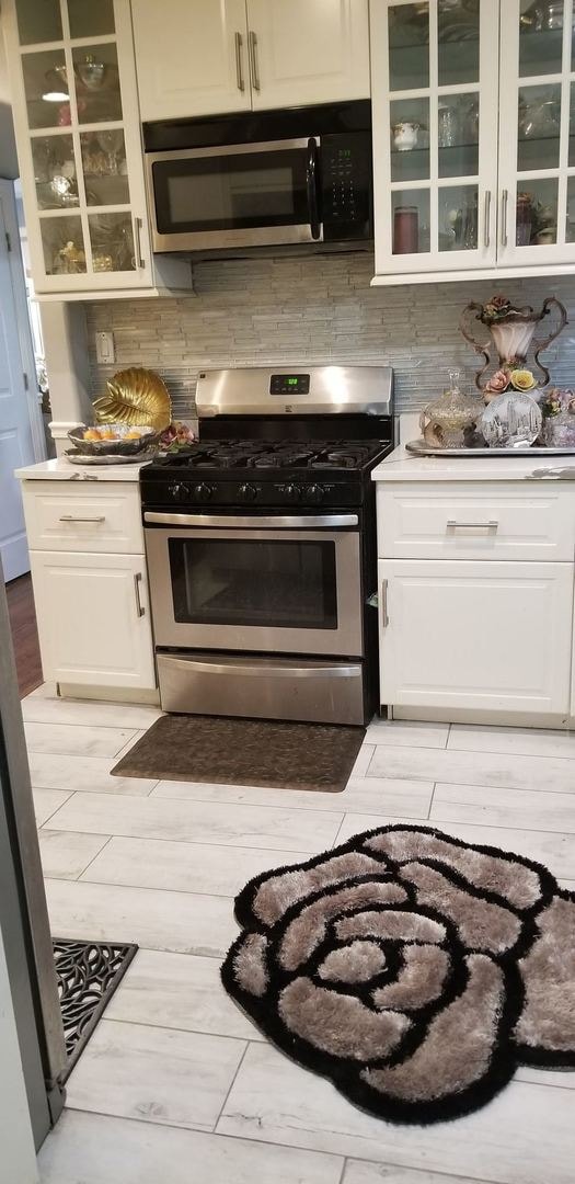 kitchen featuring white cabinets, backsplash, and appliances with stainless steel finishes