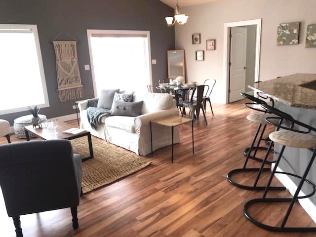 living room with a notable chandelier, lofted ceiling, and hardwood / wood-style floors