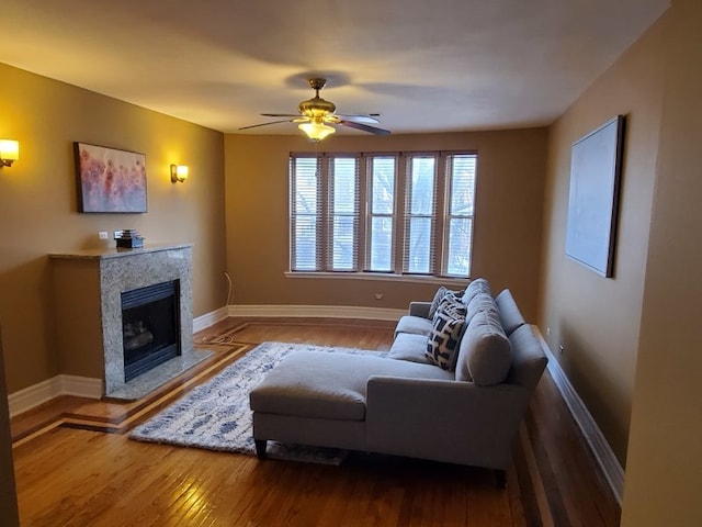 living room featuring ceiling fan, dark wood-type flooring, and a premium fireplace